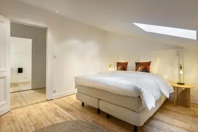 a white bedroom with a large bed and a skylight at The 1894 Boutique Holiday Apartment in Antwerp