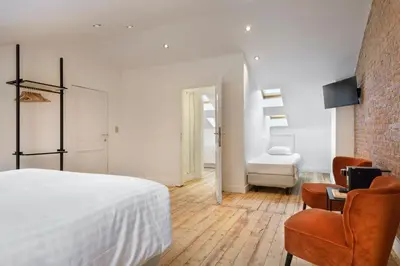 a bedroom with a white bed and a chair at Our Bird's Nest in the Heart of Antwerp in Antwerp