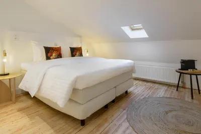 a bedroom with a large white bed and wooden floors at Our Bird's Nest in the Heart of Antwerp in Antwerp
