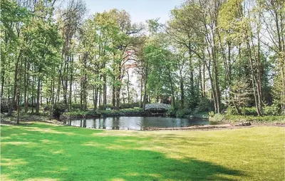 a pond in the middle of a field with trees at Kasteel Ter Leyen in Assenede