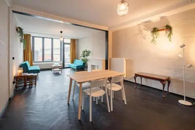 a dining room with a table and chairs and a room with windows at Charming and Spacious Apartments in the Heart of Antwerp in Antwerp