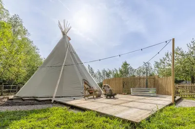 a teepee tent in a yard with a wooden deck at Tipi Bo Deluxe in Kaprijke