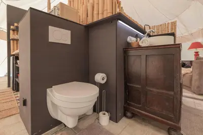 a bathroom with a toilet and a wooden cabinet at Tipi Bo Deluxe in Kaprijke