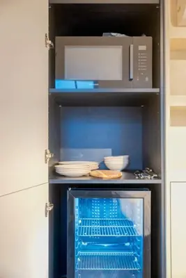 a kitchen with a microwave and dishes on shelves at Charming Attic Studio in Ghent in Ghent