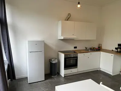 a small kitchen with white cabinets and a refrigerator at Bruxelles midi flat in Brussels