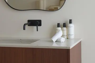 a bathroom counter with three bottles of soap and a mirror at SHWAY - The Book Binder in Antwerp