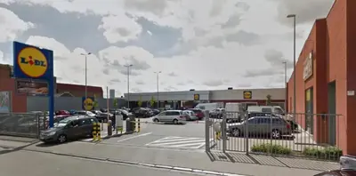 a parking lot with cars parked in front of a car dealership at Appartement Bruxelles Belgique in Brussels