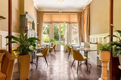 a restaurant with tables and chairs and plants at Boutique Baron Osy Suite Second Street in Antwerp