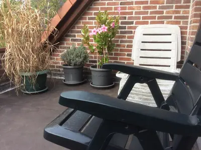 a black bench sitting on a patio with potted plants at Cosy attic apartment, terrace, 1 bedroom, double bed for 2 plus single bed if 3 guests in Buggenhout