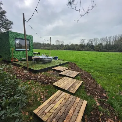 a tiny house with a table and a tub in a field at Kromven Puur Genieten in Merksplas