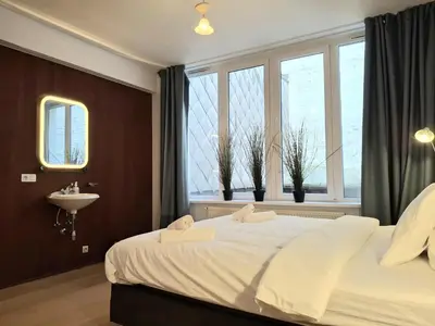 a bedroom with a bed and a sink and windows at Central in the heart of Brussels in Brussels