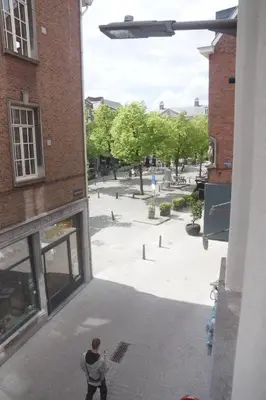 a man standing outside of a building looking at a courtyard at Stadsstudio Antwerpen in Antwerp