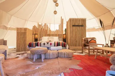 a room with a tent with a couch and chairs at Tipi Bo exclusief in Kaprijke