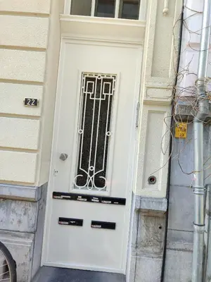 a white door with a metal grill on a building at cosy studio2 in Antwerp