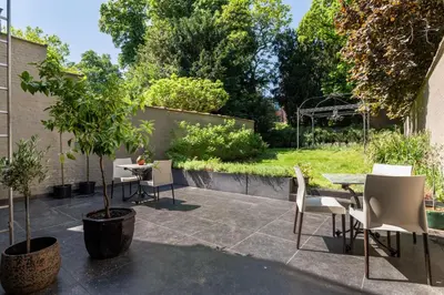 a patio with chairs and a table and a tree at Boutique Cogels Osy Suite Four Garden in Antwerp