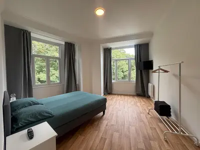 a bedroom with a green bed and two windows at Basilique Brussels 2 in Brussels