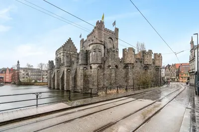 an old castle next to a river with train tracks at Charmante Studio op Toplocatie - Hartje Gent in Ghent