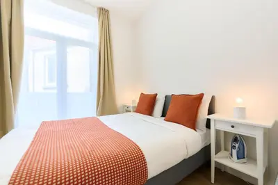 a bedroom with a bed with orange pillows and a window at Apartment Wiels 3 in Brussels