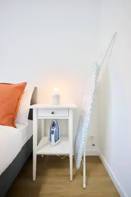 a white bedside table with a blue alarm clock on it at Apartment Combaz 4 in Mellet