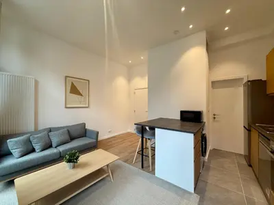 a living room with a blue couch and a table at The Modern Nest - Jourdan in Brussels
