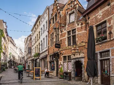 a man riding a bike down a street with buildings at Wonderful apartment in Sablon in Brussels