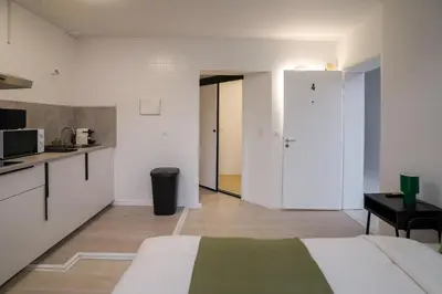 a white room with a bed and a kitchen at Jourdan 4 in Brussels