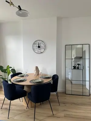 a dining room table with chairs and a clock on the wall at 5- Nid lumineux 2 chambres au plein coeur d'Ixelles in Brussels