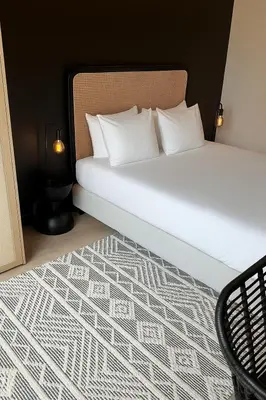 a bed with white pillows and a black and white carpet at Modern 2-Bedroom Apartment for 4 Guests, In a Prime Location Close to the Train Station and the Historic Center of Ghent in Ghent