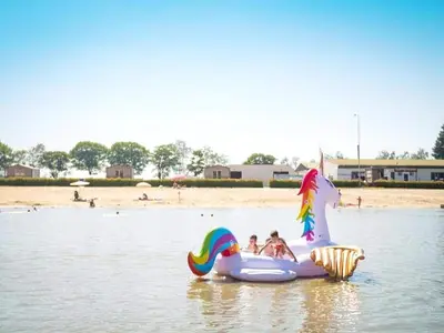 two children are riding on an inflatable unicorn in the water at 3-Bedroom Central Retreat in Ravels in Ravels