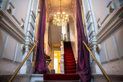 a staircase with purple curtains and a chandelier at Papillon Boutique Villa Centre Antwerp in Antwerp