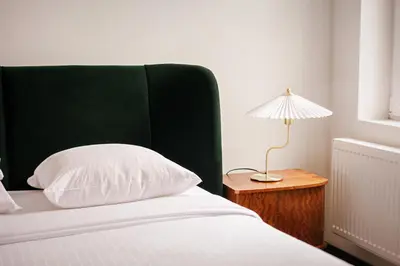 a bed with a green headboard and a lamp on a table at Central Ghent Apartment for 3 Guests in Ghent