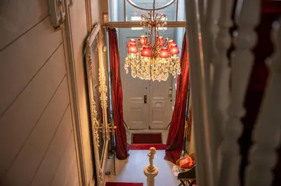 a chandelier in front of a door with red curtains at Le Nymphale Suite Antwerp in Antwerp