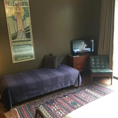 a bedroom with a bed and a tv and a chair at Baeten's bed and breakfast in Ghent