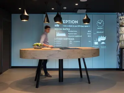 a man standing behind a wooden table with a person behind it at ibis Aalst in Aalst