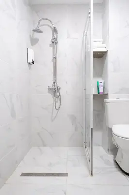a white bathroom with a shower and a toilet at Hotel Le Grand Colombier in Brussels