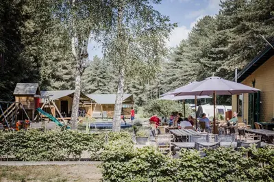 a group of people sitting at a table with an umbrella at Camping Siesta in Lille