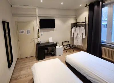 a bedroom with two beds and a desk and a table at Albert - Rooms in Mechelen