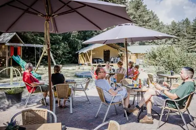 a group of people sitting at tables under an umbrella at Camping Siësta in Lille