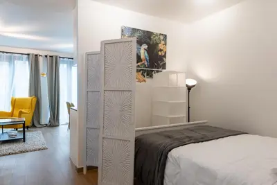a white bedroom with a bed and a yellow chair at Royal Arts-Loi Studio in Brussels