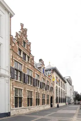 a large brick building with flags on a street at SHWAY - The Card Room Green Studio in Antwerp