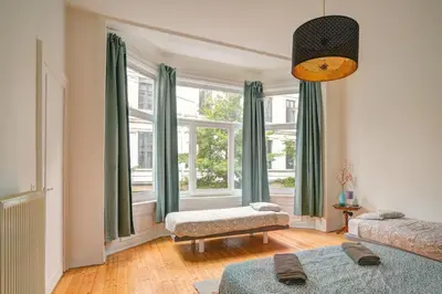 a living room with a large window with green curtains at Theodore Residence in the Heart of Antwerp in Antwerp