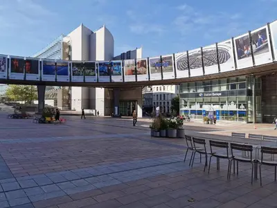 a bridge over a plaza with chairs and a building at Charming Europarlament Resedence in Brussels