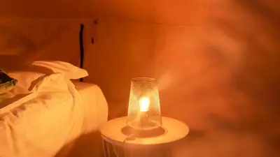 a lamp sitting on a table next to a bed at AMANI - Aap in Lichtaart