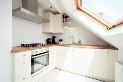 a kitchen with white cabinets and a skylight at Beautiful Terrace Apartment in the Heart of Antwerp in Antwerp