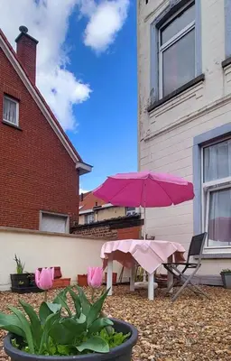 a patio with a pink umbrella and a table and chairs at Handy Studio close to Zaventem airport in Brussels