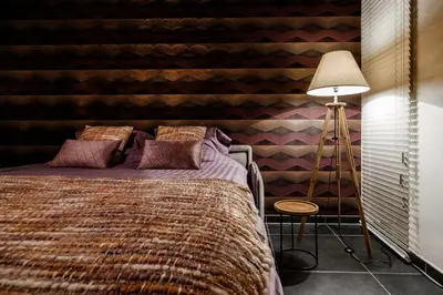 a bedroom with a bed and a striped wall at Lavendelhof luxe wellnesshouse in Zottegem