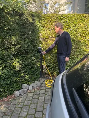 a man with a yellow hose connected to a hedge at Huis Dujardin Bed&Breakfast in Antwerp