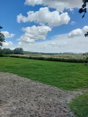 a field of grass with a blue sky and clouds at Loft aan Puyenbroeck in Wachtebeke