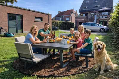 a family sitting at a picnic table with a dog at Logeerkamer XXL 25 m2 in Zemst