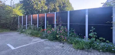 a fence with a bunch of flowers in a parking lot at Fitness loft 50 m2 in Zemst